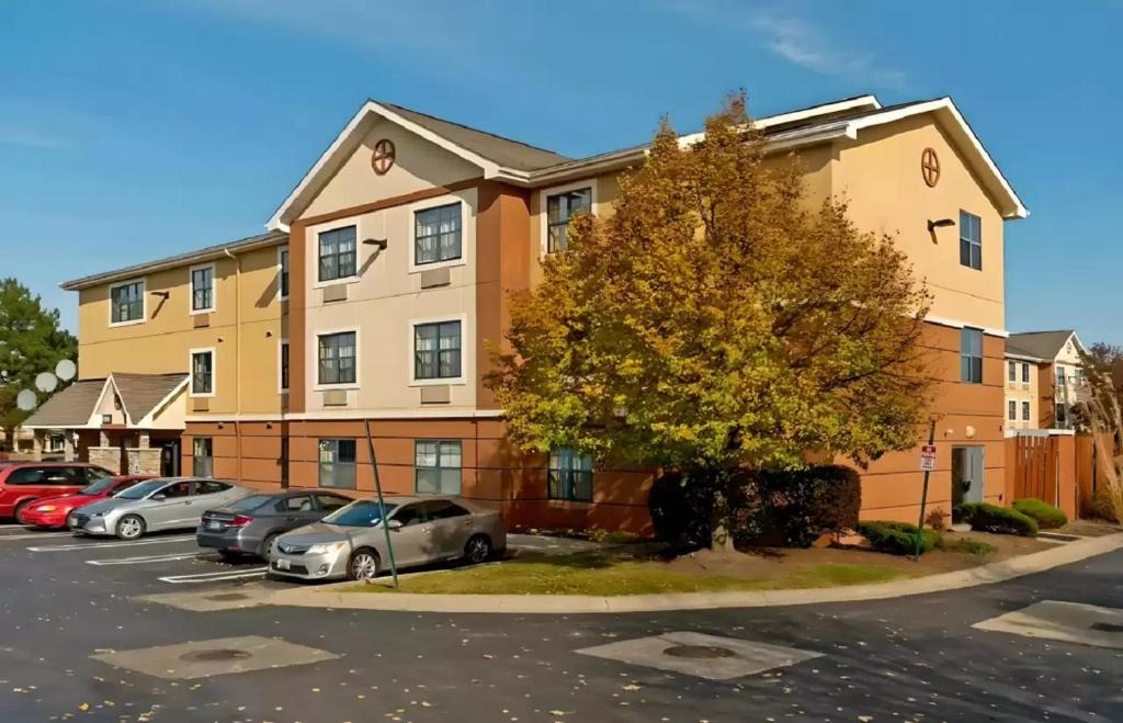 a apartment building with cars parked in a parking lot at Suburban Studios in Auburn Hills