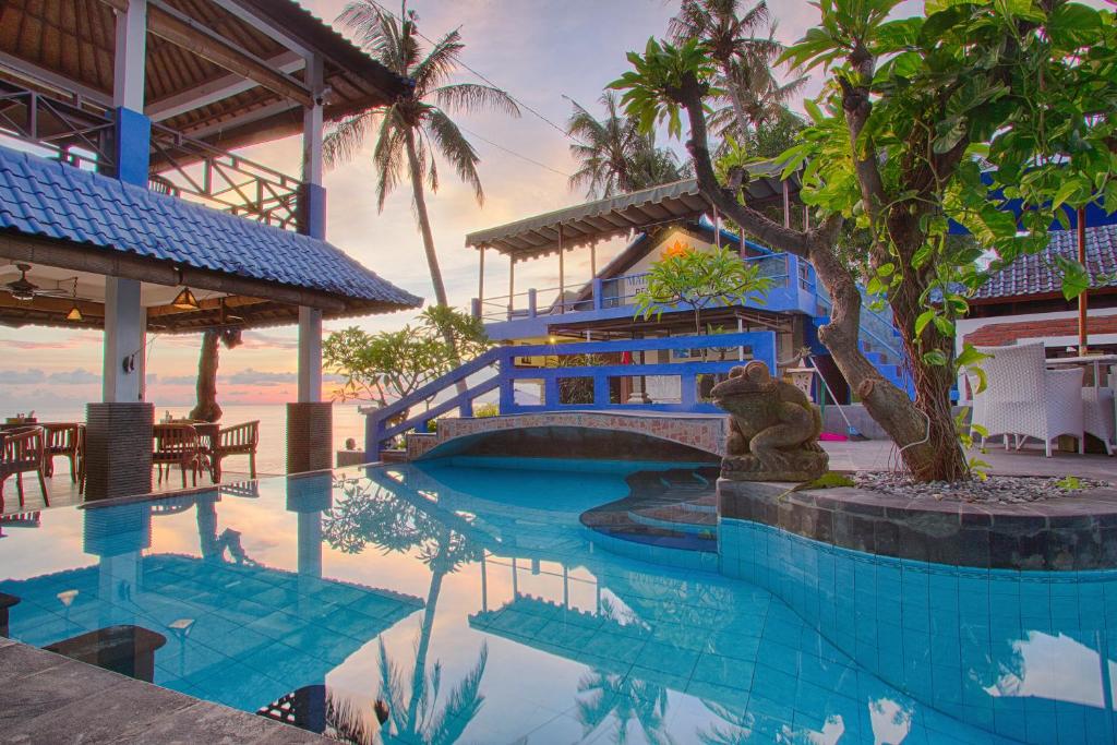 una piscina del complejo con un osito de peluche sentado al lado de un edificio en Matahari Tulamben Resort, Dive & SPA, en Tulamben