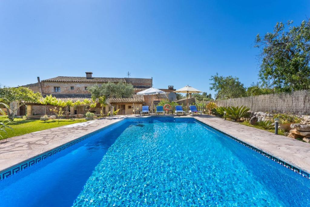 a swimming pool with blue water in front of a house at Can Nin in Santanyi