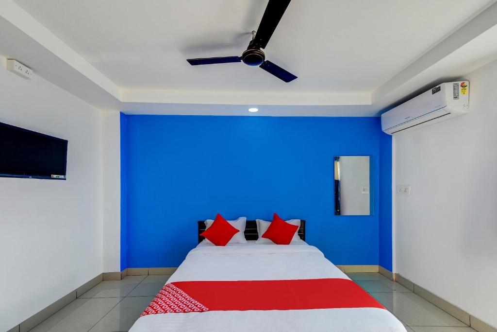a bedroom with a blue wall and a bed with red pillows at SPOT ON Hotel Utrishree in Khandagiri