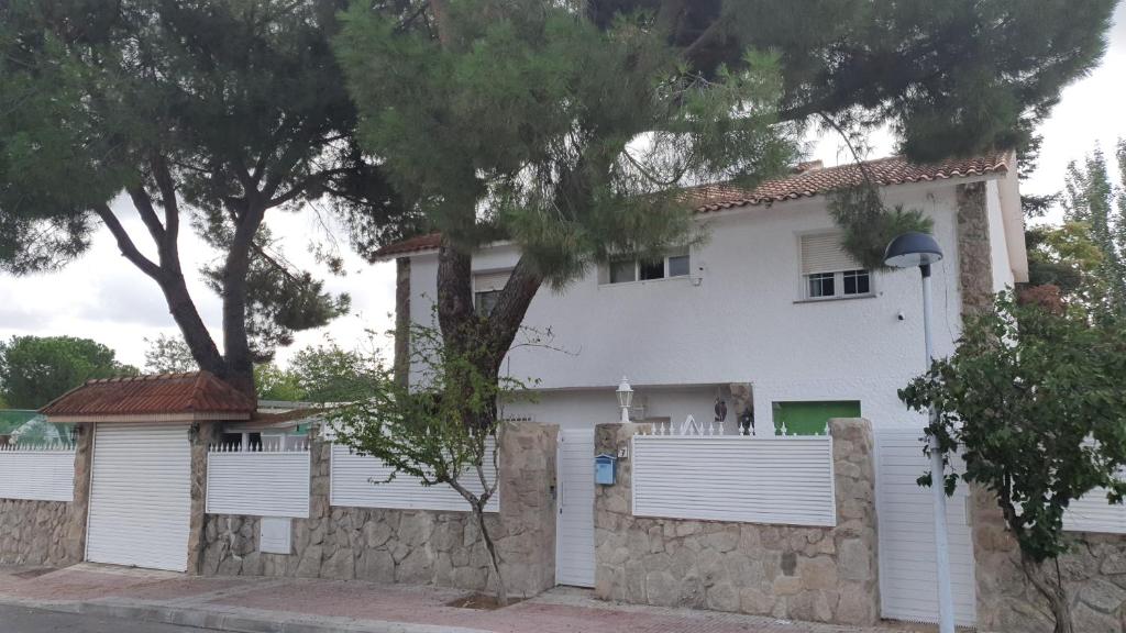 une maison blanche avec une clôture devant elle dans l'établissement Casa Pinares, à Móstoles