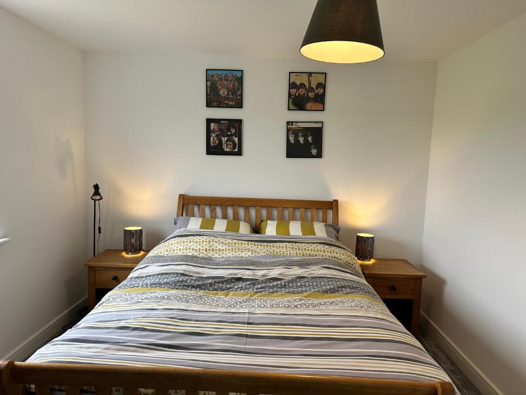 Ce lit se trouve dans une chambre dotée de 2 tables de nuit et de photos murales. dans l'établissement Bath and Bristol peaceful countryside home, à Keynsham