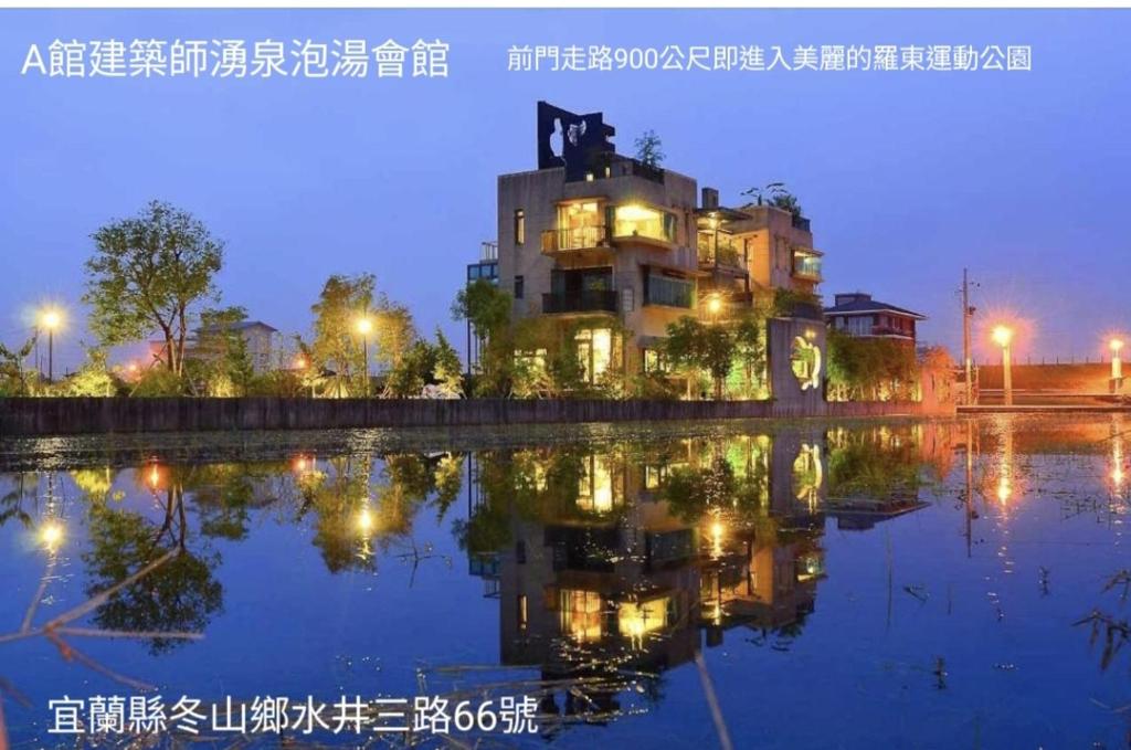 a building with its reflection in the water at night at 建築師湧泉泡湯會館 in Dongshan