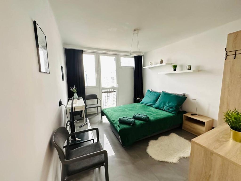 een kleine kamer met een groen bed en stoelen bij Warsaw City Center Rooms in Warschau