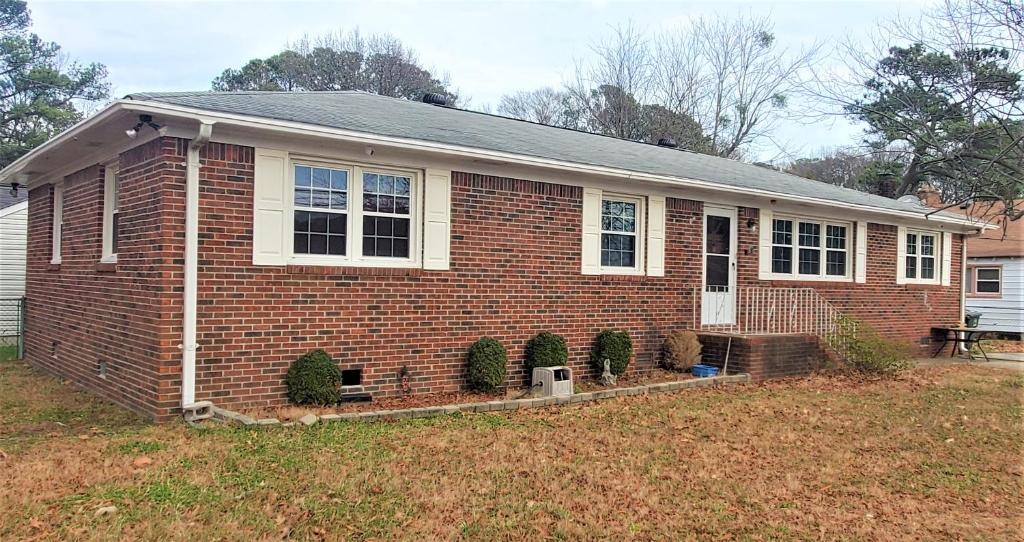 Uma casa de tijolos com três árvores de Natal à frente. em Beautiful Ranch Home Between Virginia Beach and Norfolk em Virginia Beach