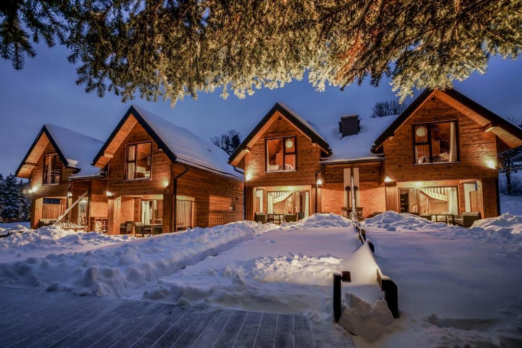 une maison recouverte de neige la nuit dans l'établissement Novosiele Residence - nad górską rzeką - Leśne Spa sauna jacuzzi - Bieszczady, à Bystre