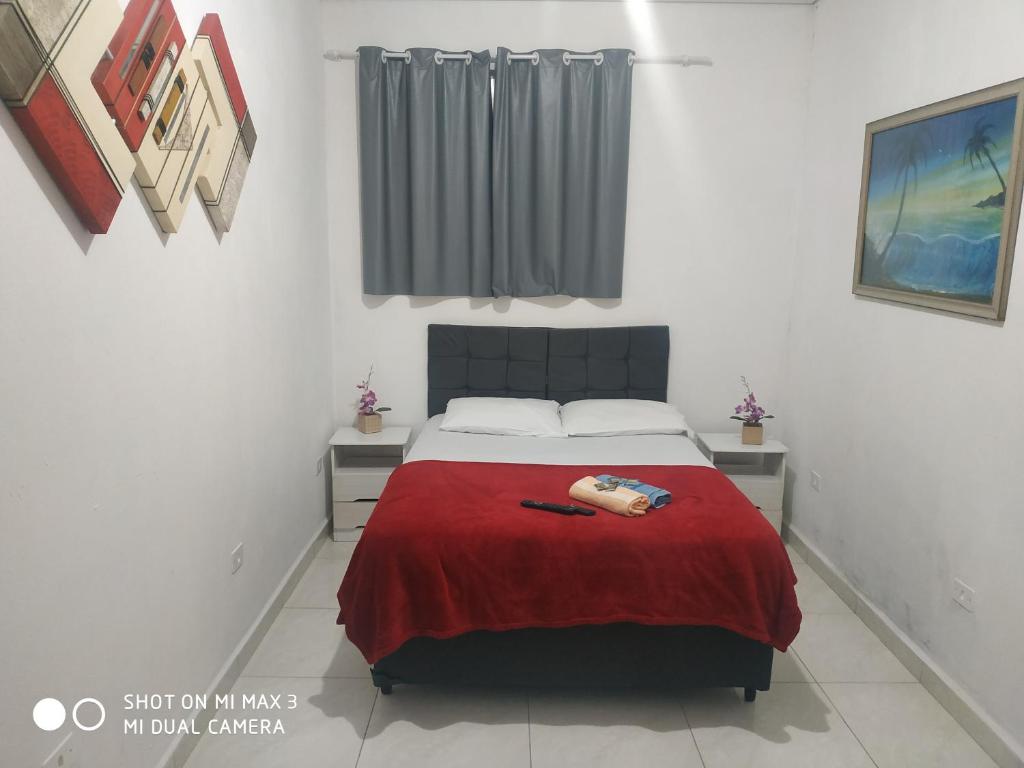 a bedroom with a bed with a red blanket at Pousada Praia Grande Solemar in Praia Grande