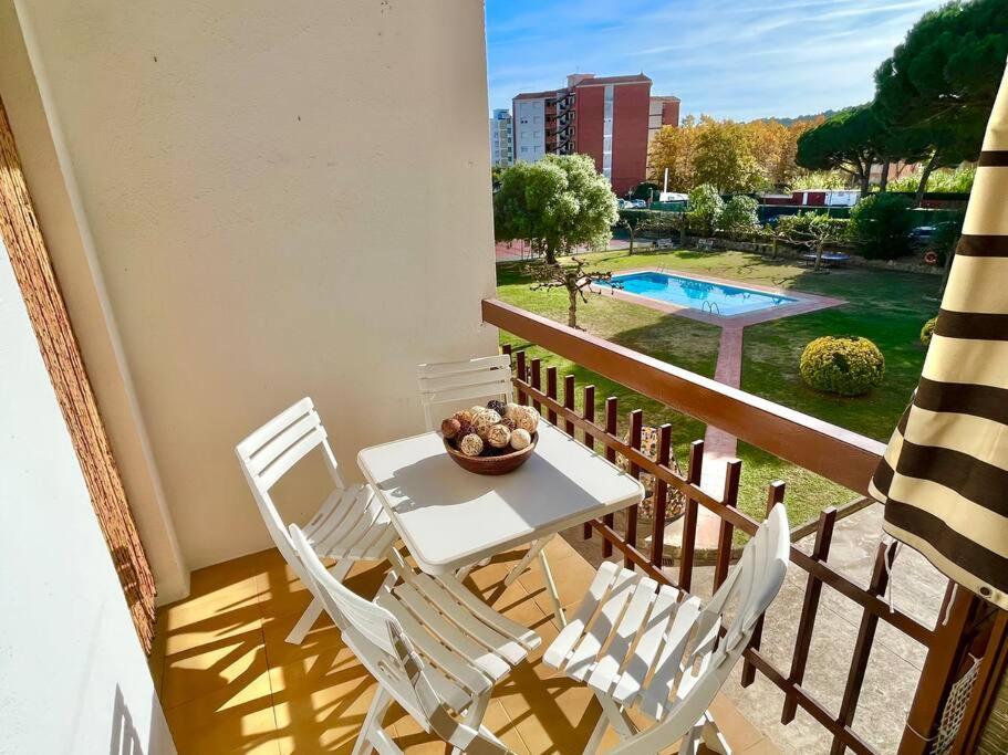 balcón con mesa, sillas y piscina en Encantador apartamento en Playa de Aro, en Playa de Aro