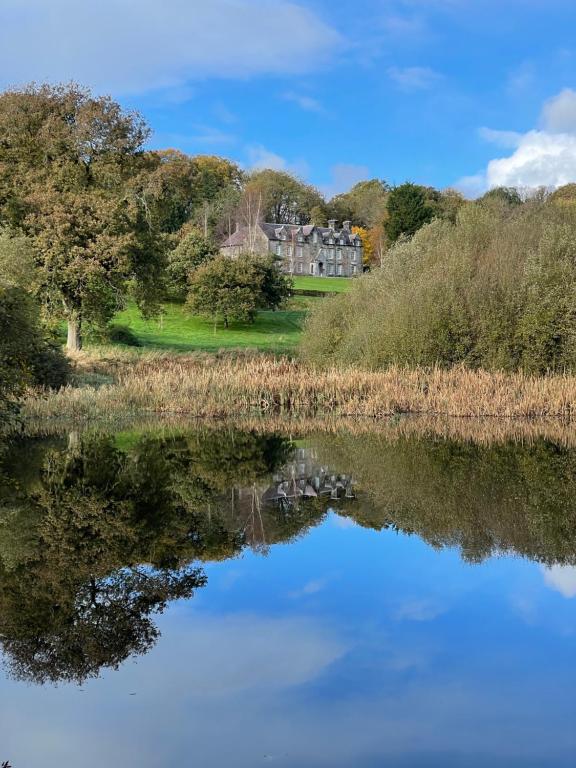 una casa si riflette nell'acqua di un lago di Noyadd Trefawr a Cardigan