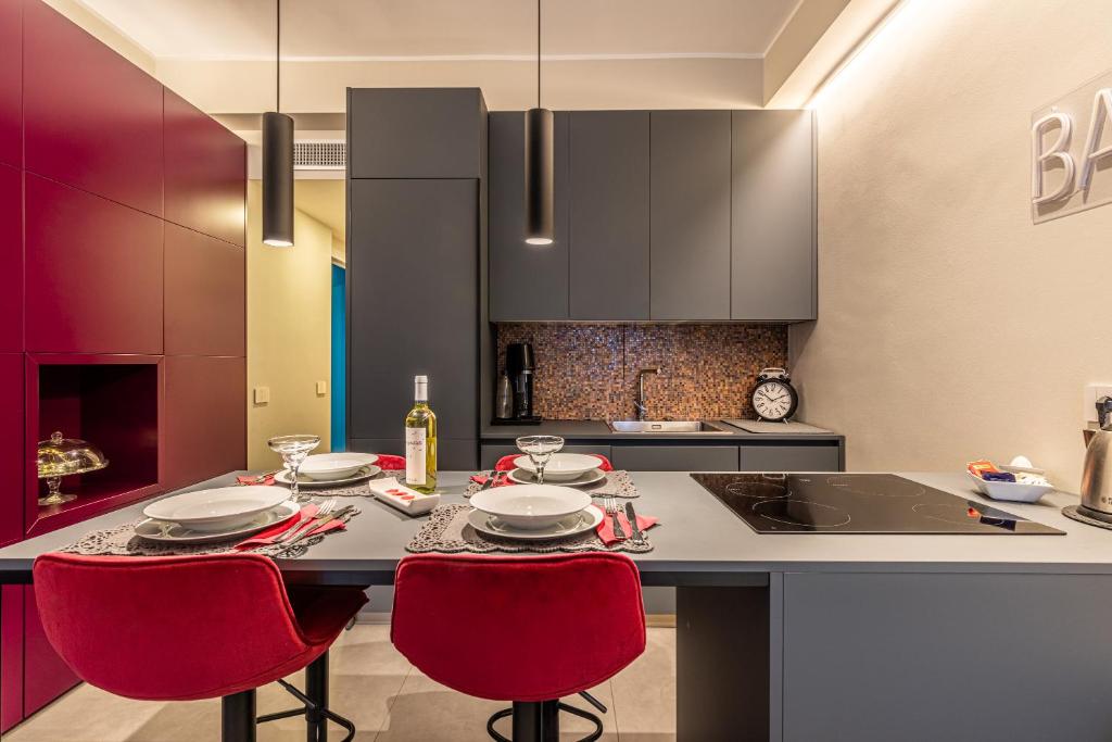 Una cocina con sillas rojas y una mesa con platos encima. en Duomo a 2 fermate - Tiny Apartment in Pta Venezia, en Milán