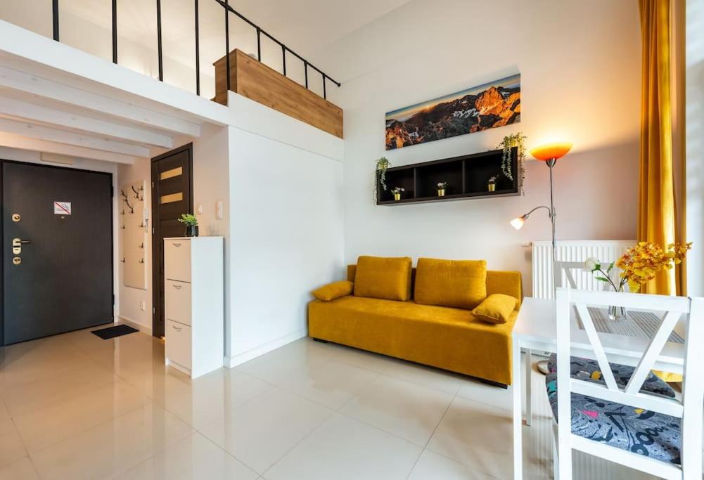 sala de estar con sofá amarillo y escalera en Apartment Mountain 40m2 balkon antresola 4 osoby, en Cracovia