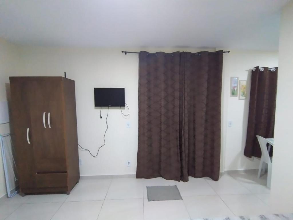 uma sala de estar com televisão e cortina em Suites para casais na praça Oswaldo Cruz em Cabo Frio