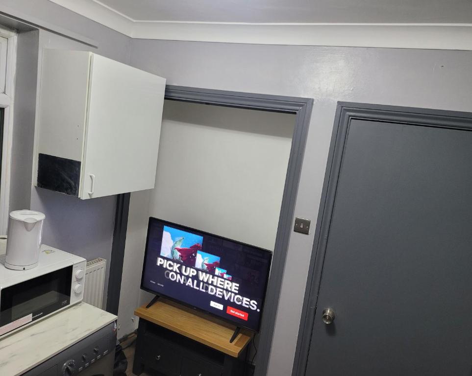 a room with a tv and a door with a microwave at Sleek 2 bedroom flat-sleeps up to 5 guest in Hornchurch