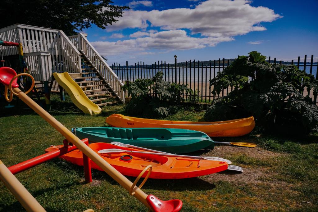 un grupo de kayaks en el césped junto a una valla en Cabañas Kompatzki, en Ancud