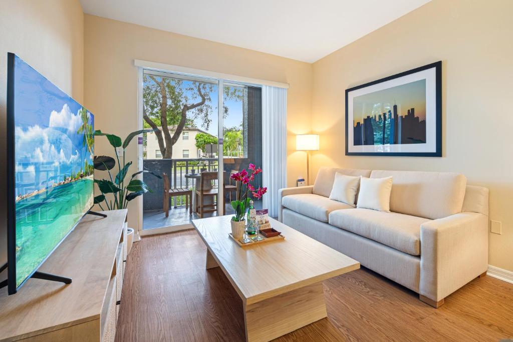 a living room with a couch and a tv at Dharma Home Suites South Miami at Red Road Commons in Miami