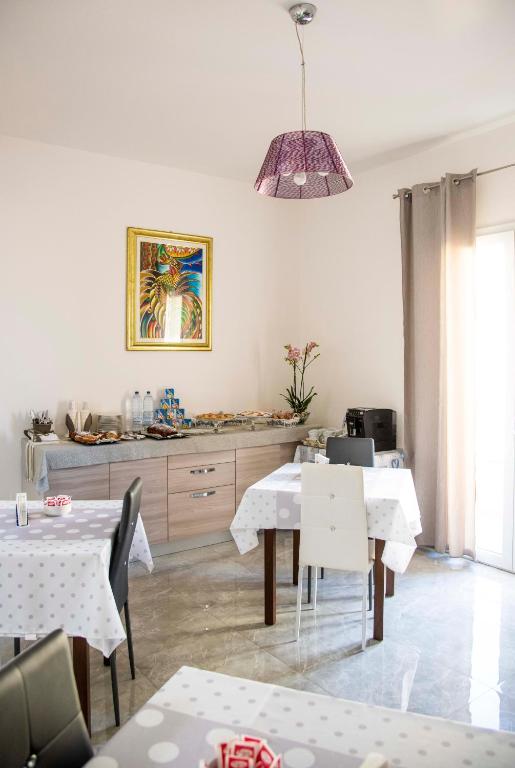 a dining room with white tables and a pendant light at Blu Mare Lampedusa Bed And Breakfast in Lampedusa