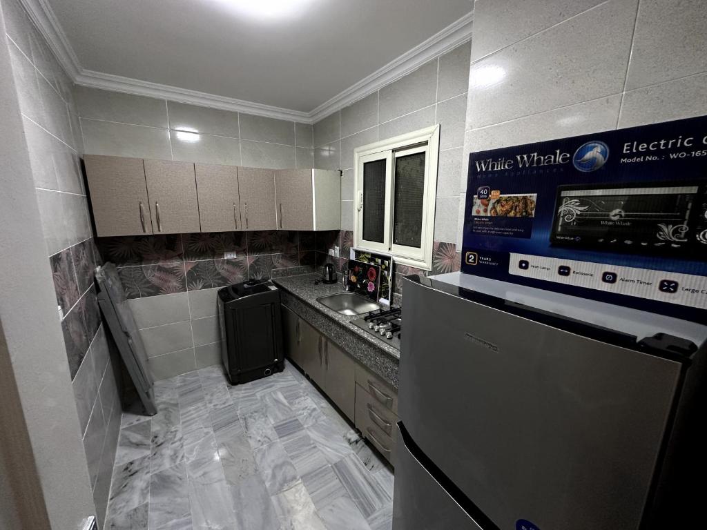 a small kitchen with a refrigerator and a sink at شقة فندقية 108 in Cairo