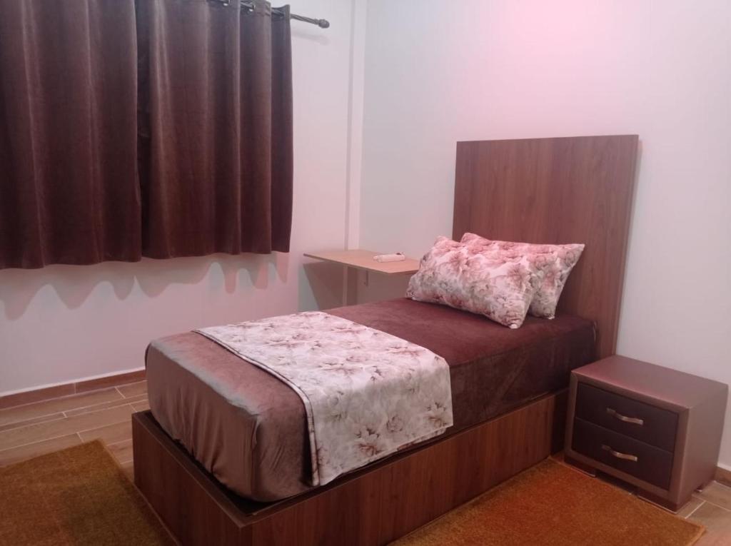 - une chambre avec un lit et une tête de lit en bois dans l'établissement Appartement luxueux à louer à Taounate, à Taounate