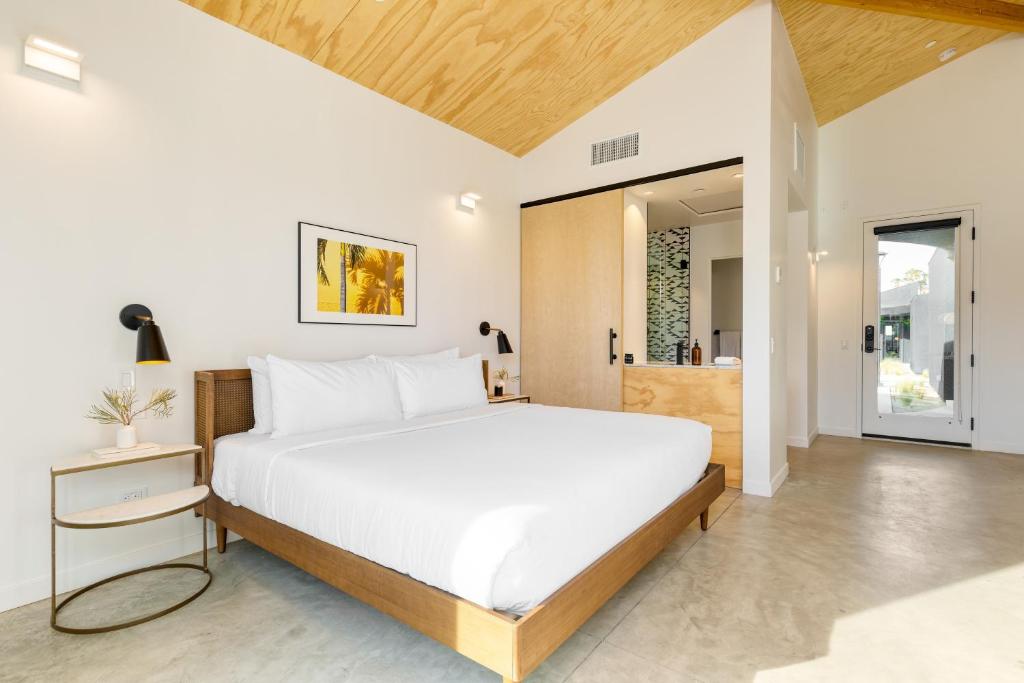 a bedroom with a large bed and a bathroom at Blackhaus by AvantStay ADA Modern Rooms, Pool & BBQ in Palm Springs