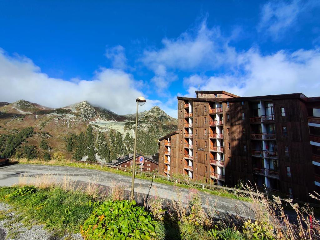 un bâtiment sur une colline avec des montagnes en arrière-plan dans l'établissement Arc 2000 - Charmant appartement 4 personnes, chambre séparée, calme et en plein centre, à Bourg-Saint-Maurice