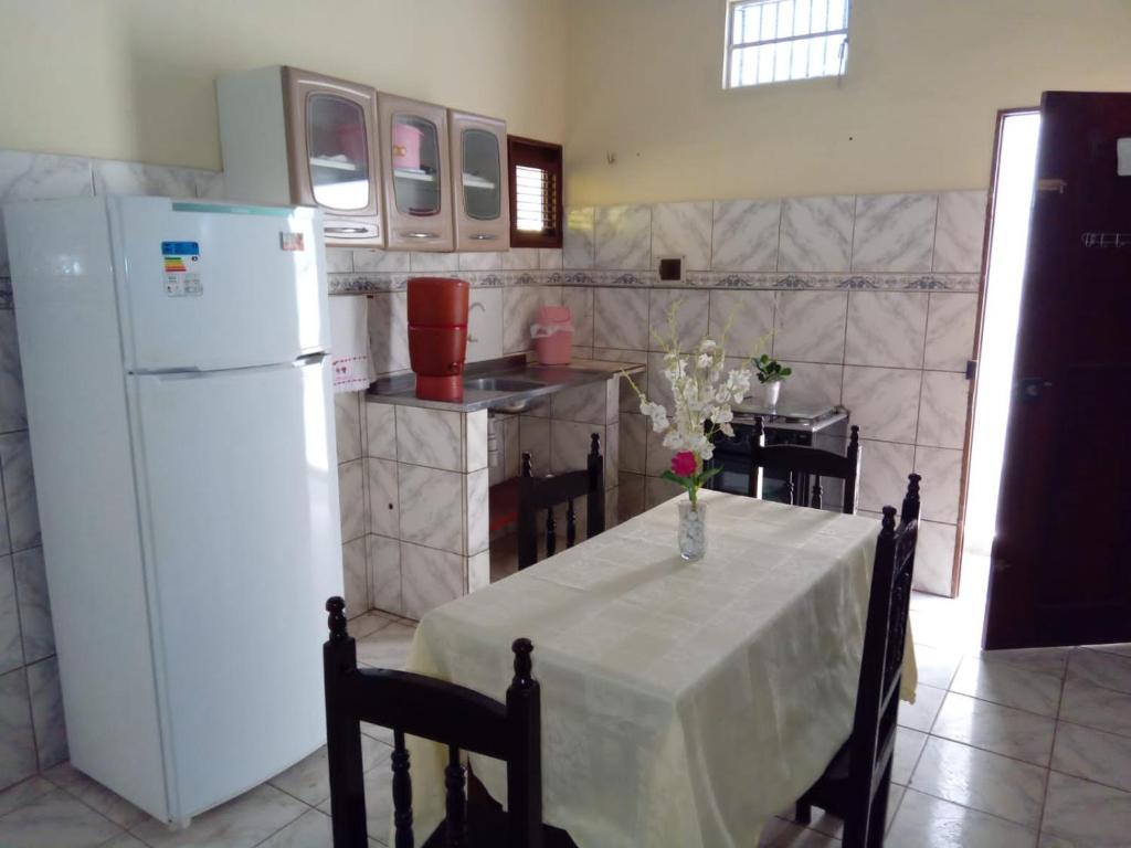 a kitchen with a table and a white refrigerator at Aconchego da Vó in Barreirinhas