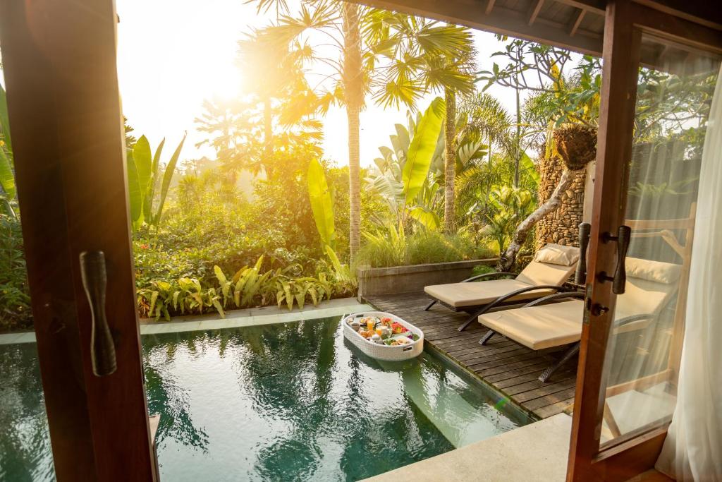 a room with a view of a pool with a bowl of food at Nau Villa Ubud in Tegalalang