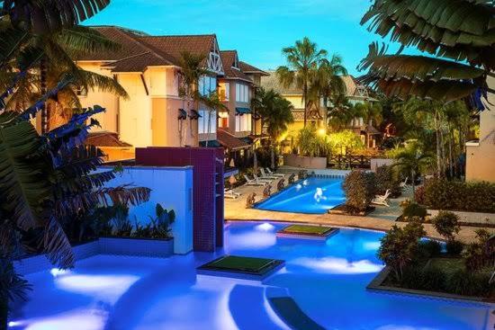 Edge Hill的住宿－Lakes Resort 1 Bedroom Apartment，一个带棕榈树和房屋的游泳池的度假酒店