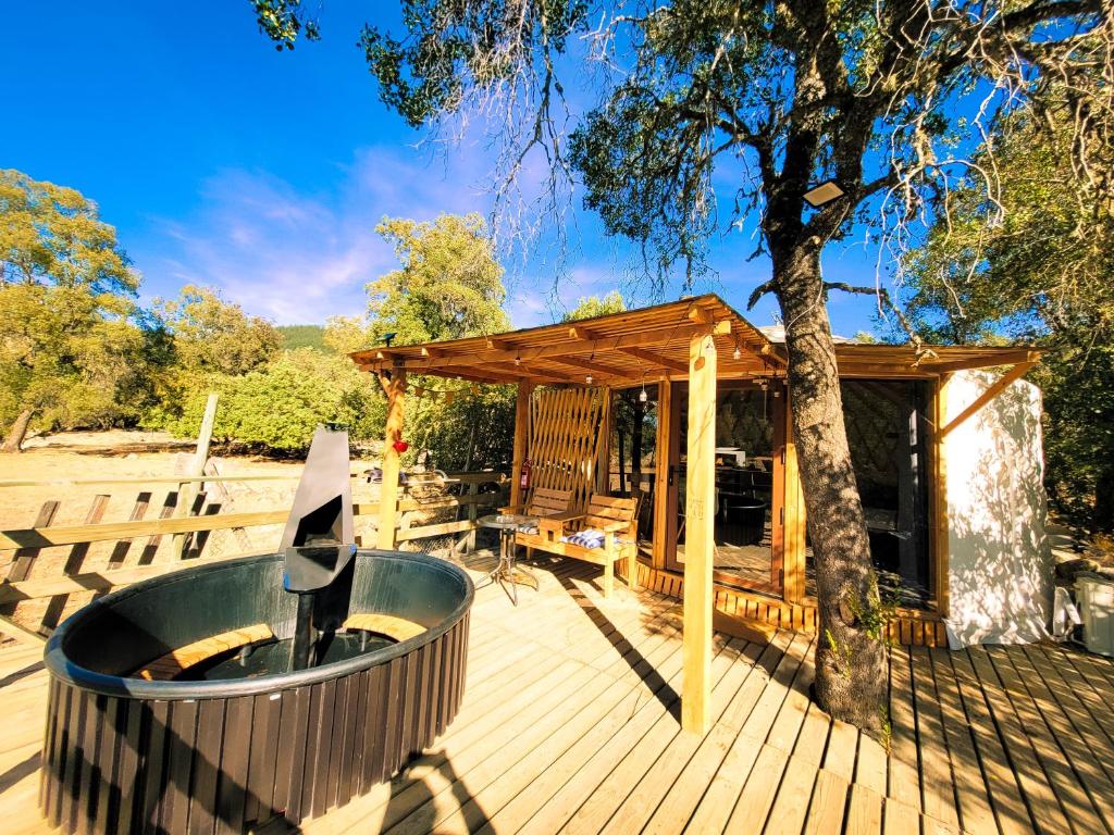 une terrasse en bois avec un arbre et un bain à remous dans l'établissement Cabaña con hot tub privada y vista al río, à Linares