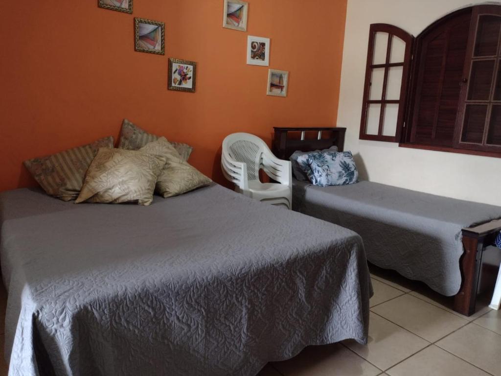 a bedroom with two beds and a chair and a window at Conforto e simplicidade! Casa top com garagem, cozinha, banheiro e quarto in Cabo Frio