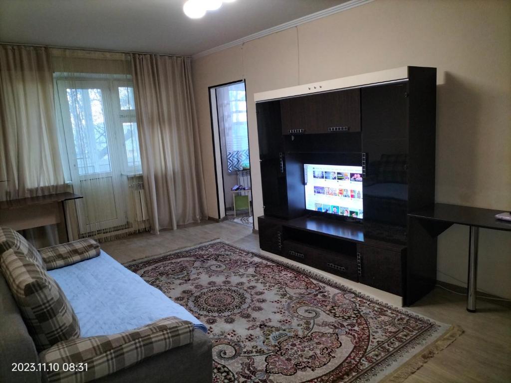 a living room with a television and a couch at Квартира in Shymkent