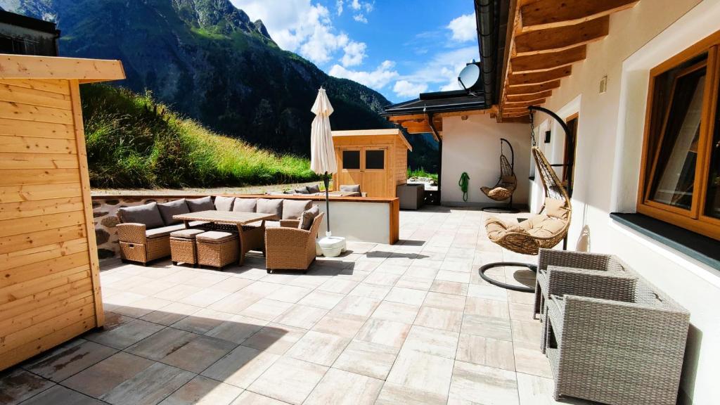 eine Terrasse mit einem Tisch, Stühlen und einem Berg in der Unterkunft Haus Bergjuwel in Huben