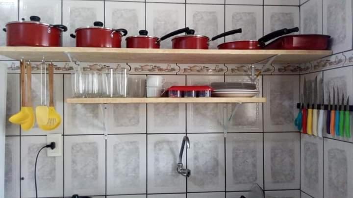 uma cozinha com panelas e frigideiras vermelhas nas prateleiras em Hostel Resende em Resende