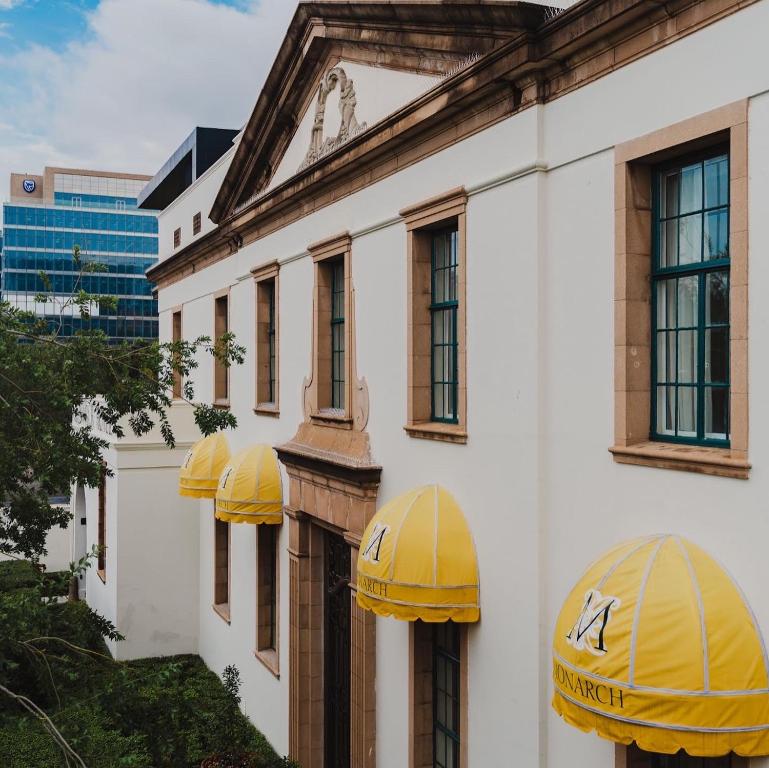 un edificio con sombrillas amarillas a un lado. en The Monarch Hotel en Johannesburgo