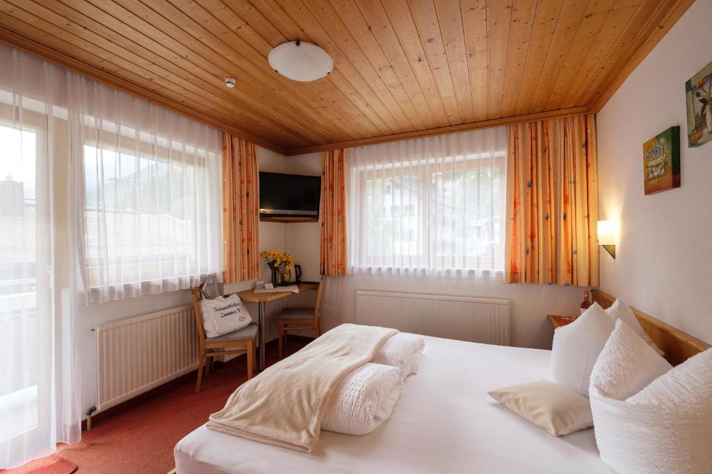 una camera da letto con un grande letto bianco in una stanza di Hotel Garni DIAS a Kappl