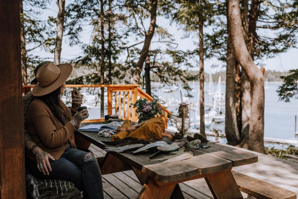 a woman sitting at a picnic table near the water at Page's Resort & Marina in Gabriola