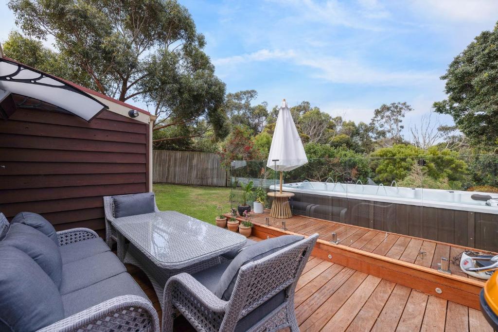 a deck with a table and chairs and an umbrella at Shiloh Beach House in Kilcunda