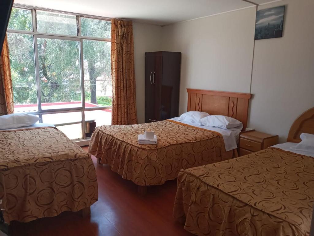 a hotel room with two beds and a window at HOTEL AREQUIPA ANDINOS in Arequipa