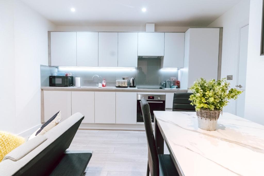 una cocina con armarios blancos y una mesa con flores. en Cosy 1Bed Apart with Wifi en Purley