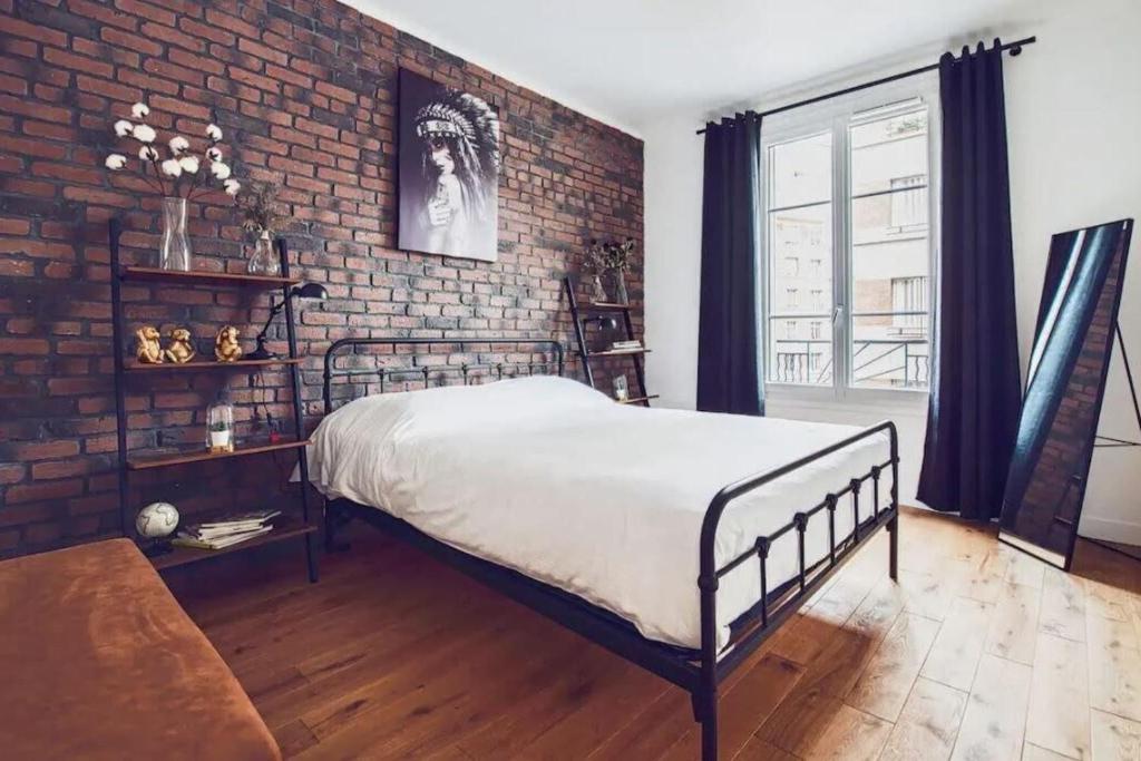 a bedroom with a bed and a brick wall at Studio Cosy Tout Confort Porte Orléans 2 Pers Paris in Montrouge