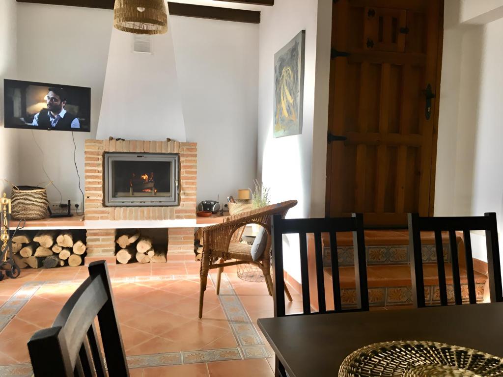 - un salon avec une cheminée, une table et des chaises dans l'établissement CASA VALLE VERDE, à Lentegí