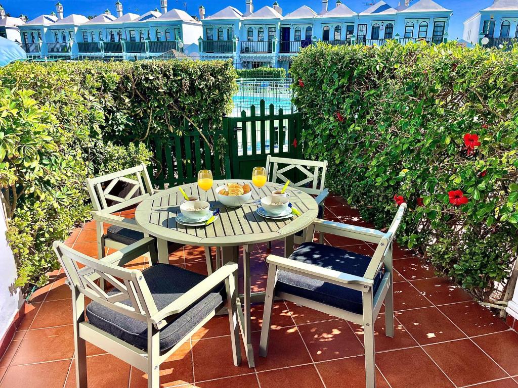 een tafel en 4 stoelen op een patio bij Bungalow Dunaflor Verde 5 by SunHousesCanarias in Maspalomas