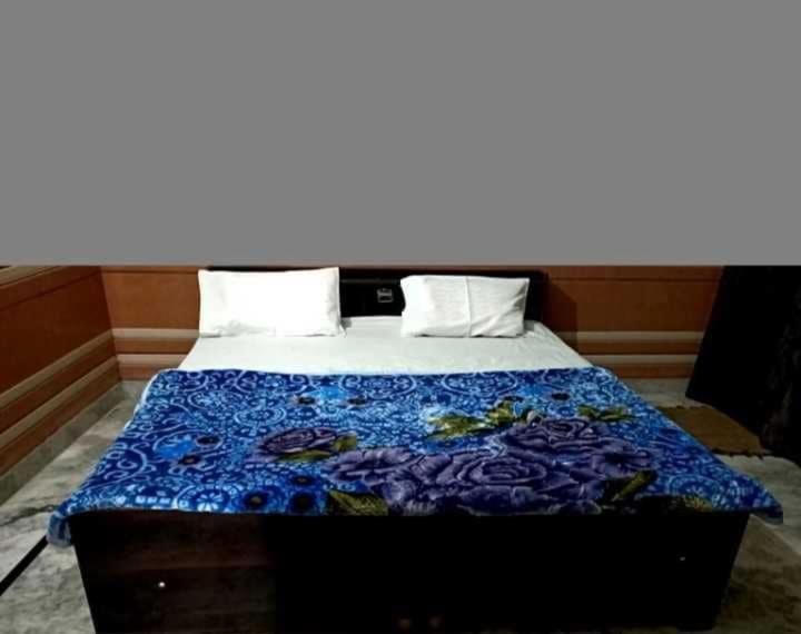 a bed with a blue blanket on top of it at OYO Kk Hotel in Meerut