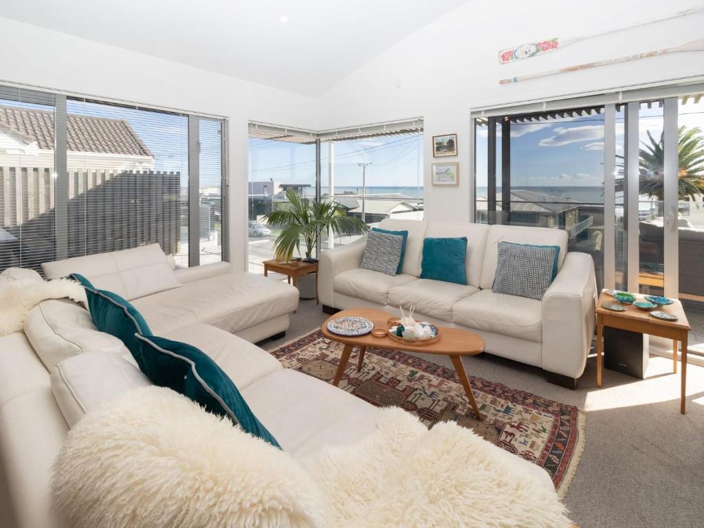 a living room with white furniture and large windows at The Ocean Outlook Pure Luxury in New Plymouth