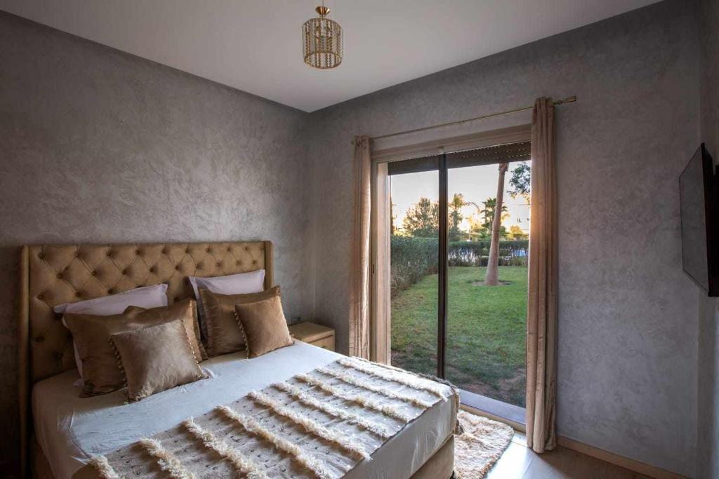 a bedroom with a bed and a sliding glass door at Prestigia golf city porte agate in Marrakesh