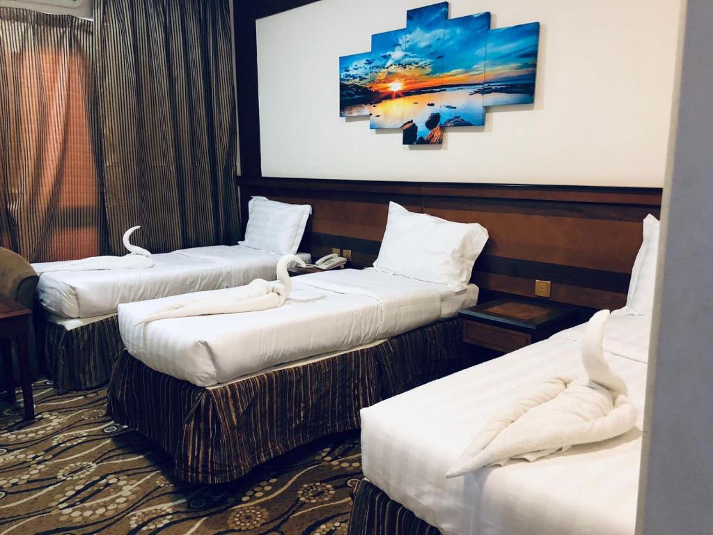 - 3 lits dans une chambre d'hôtel ornée d'une peinture murale dans l'établissement فندق الزائر الأخيار الفندقية, à La Mecque