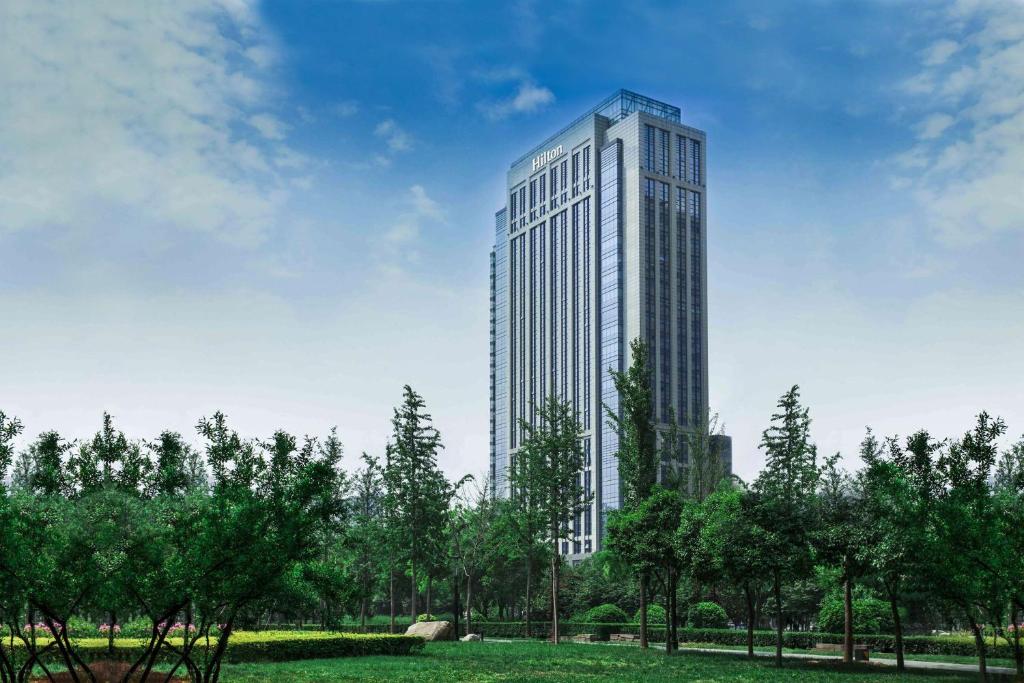 un edificio alto en un parque con árboles en Hilton Xi'an High-tech Zone, en Xi'an