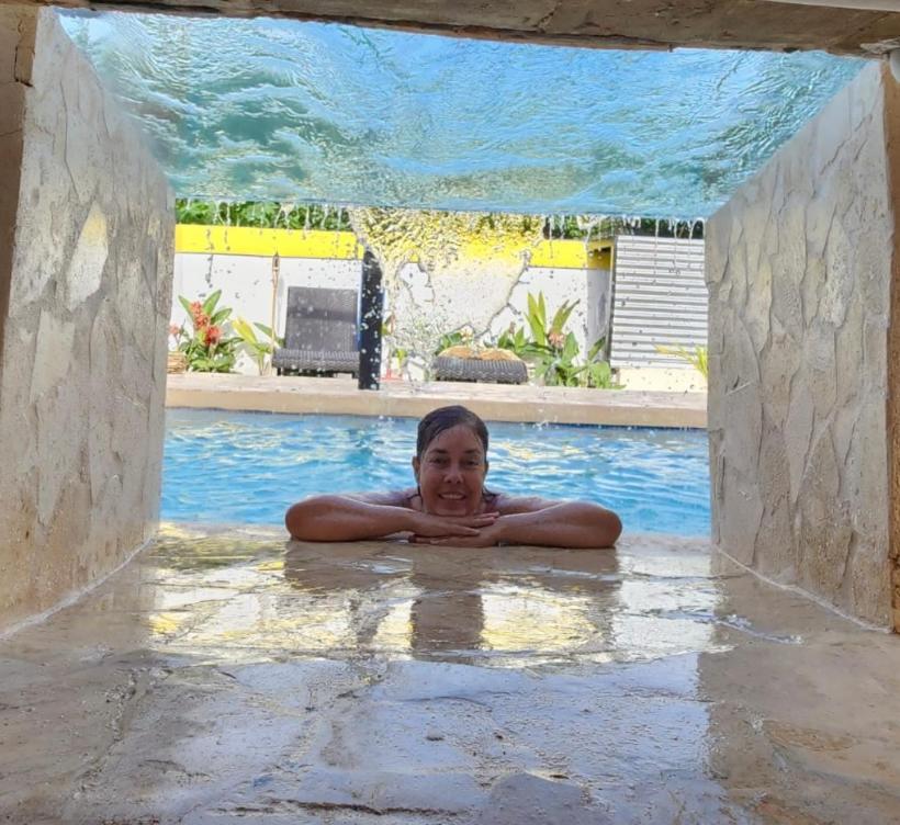 uma mulher está deitada numa piscina em Tropicoco Pool House Steps From The Beach em Puerto Nuevo