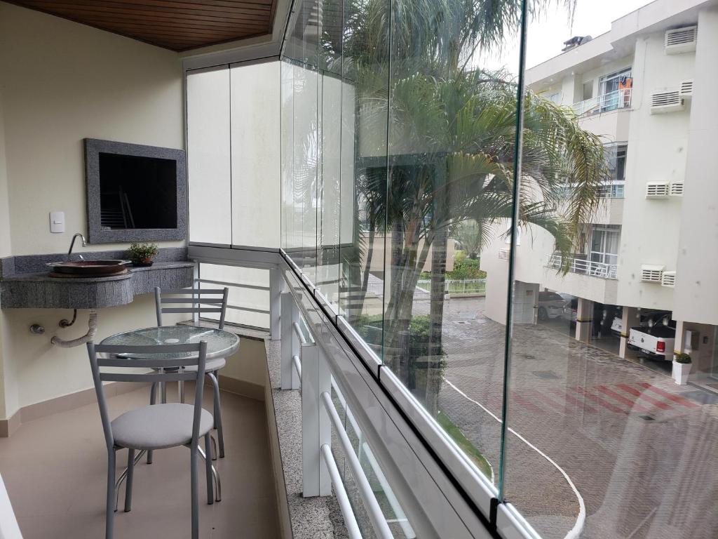 d'un balcon avec une table, une chaise et une fenêtre. dans l'établissement Apartamento na Praia Brava - Florianópolis, à Florianópolis