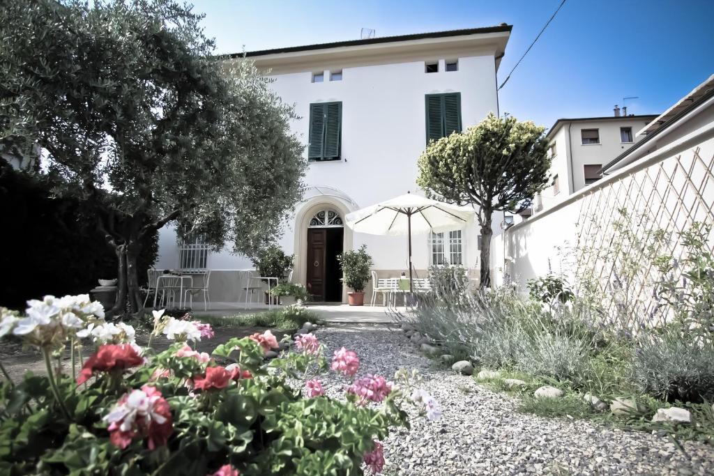 a garden in front of a white house with flowers at Lula B&B in Lucca