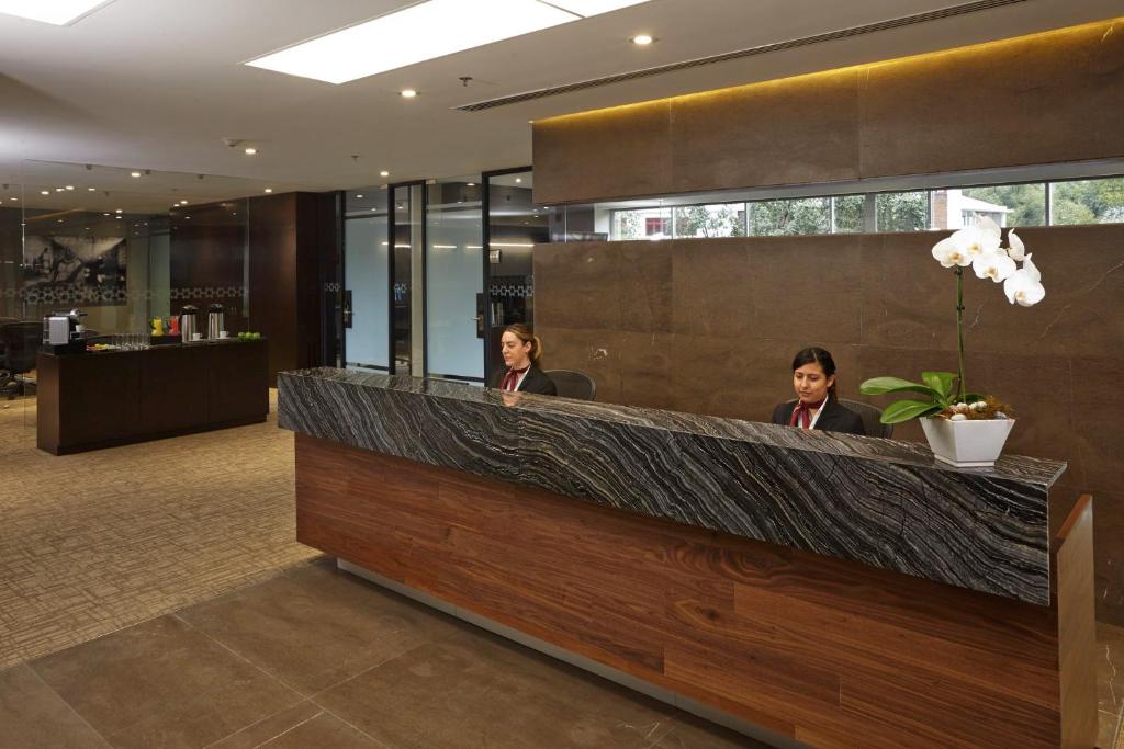 A reception area with a long stone-front desk, staffed counters, and a coffee station.